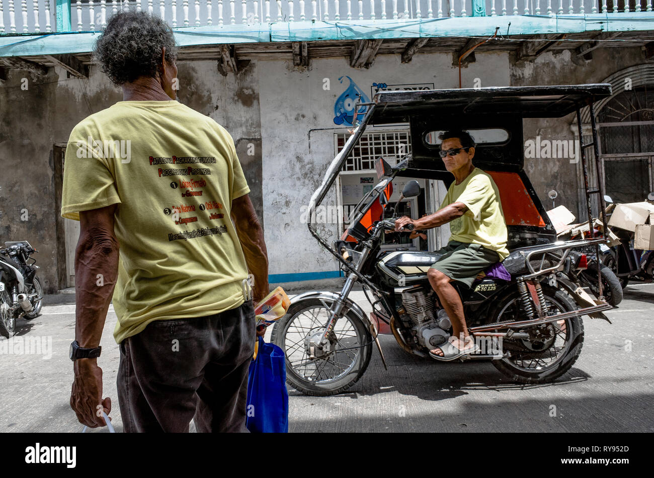 Un vieil homme de son pays un tricycle montres passent par le conducteur sur la rue - City, Philippines notamment Banque D'Images