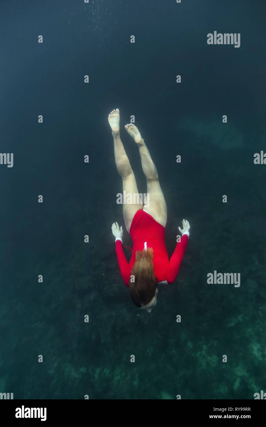 Au-dessus de la femelle en maillot rouge plongée dans l'eau bleu de mer à Bali, Indonésie Banque D'Images