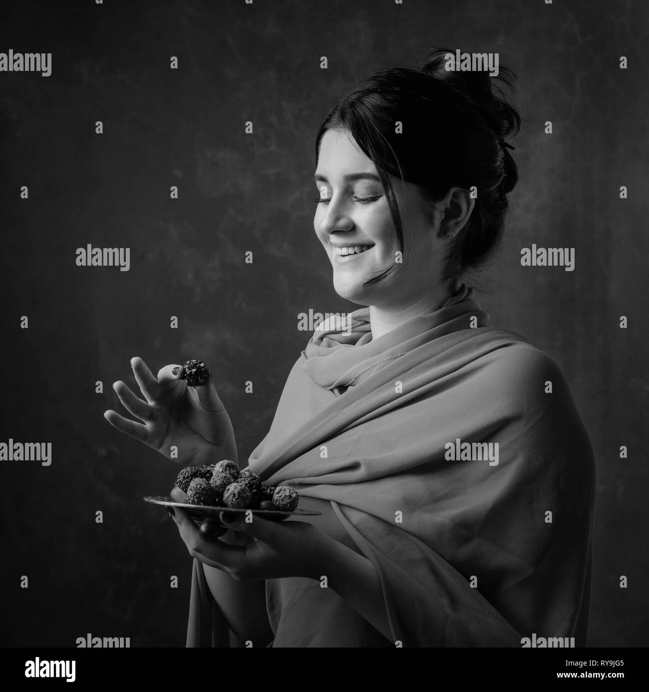 Portrait d'une jeune fille attirante avec du chocolat et des bonbons. Noir et blanc. Banque D'Images