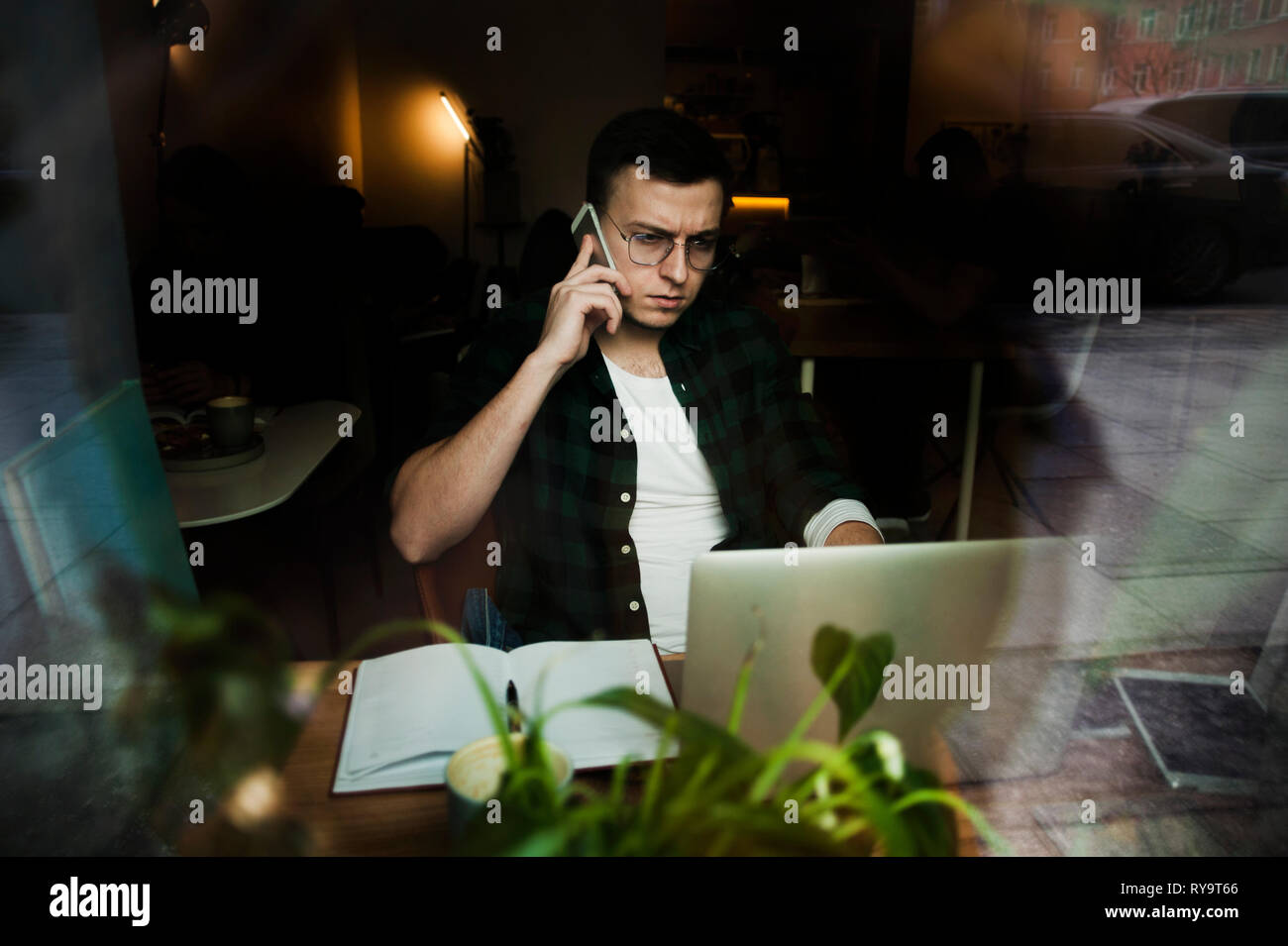 Un gars dans un café avec un ordinateur portable travaillant dans un endroit confortable avec une tasse de café, est le plaisir. Le concept de travailler en indépendant et de travailler dans le plaisir Banque D'Images