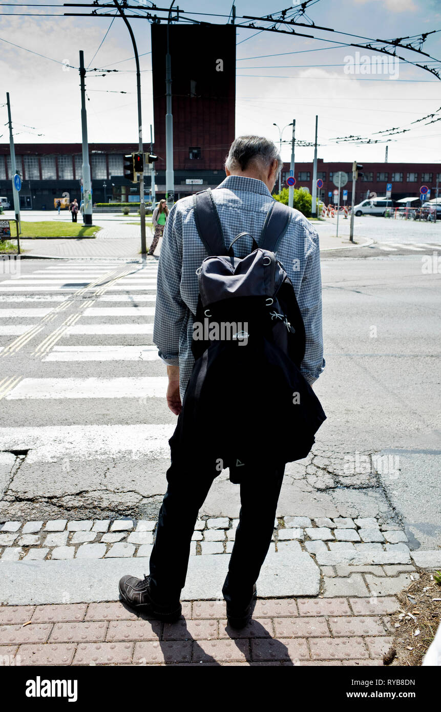 Sac à dos avec l'homme en attente de traverser la rue à un passage pour piétons Banque D'Images