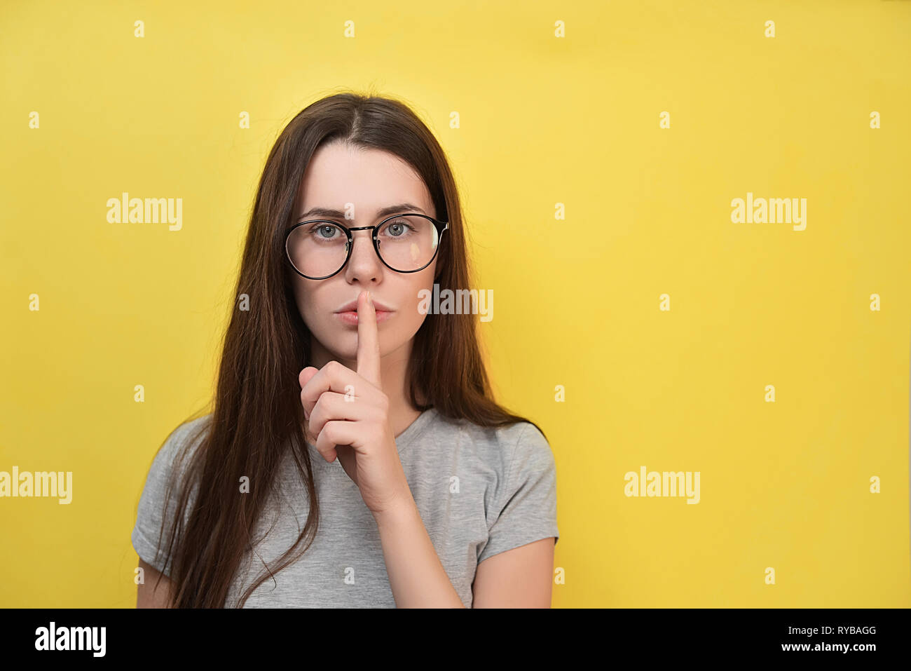 Jeune femme à lunettes avec expression perplexe, fait de silence intérieur,  de gestes d'avancement permet de rester collés sur les lèvres, de peur que  quelqu'un de révéler son secret, se trouve un