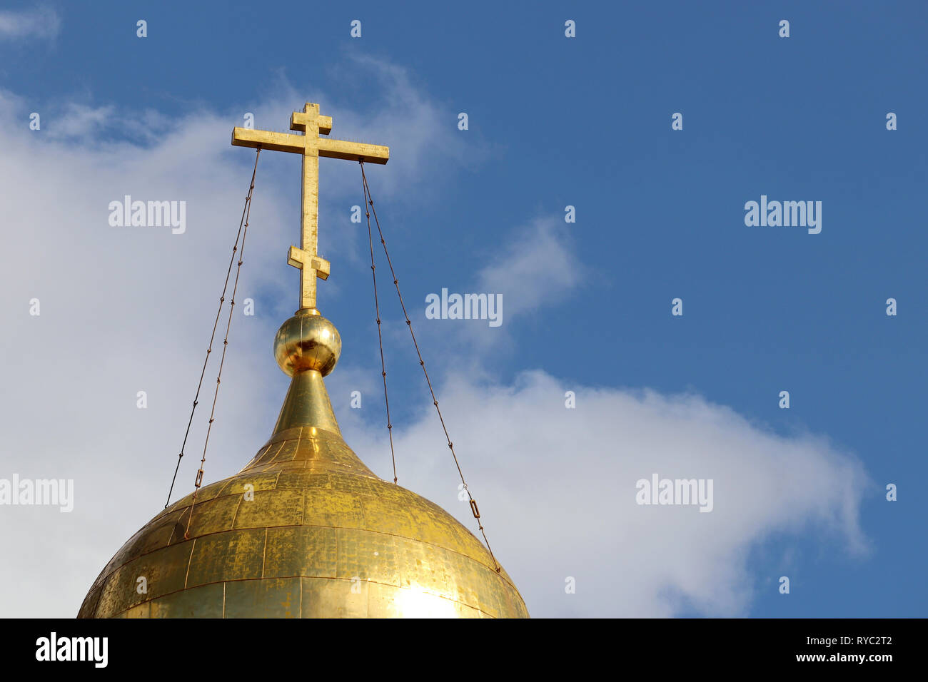 Dôme doré de l'Église orthodoxe d'une croix contre le ciel bleu avec des nuages blancs. Temple chrétien, arrière-plan de carte de vœux religieux Banque D'Images