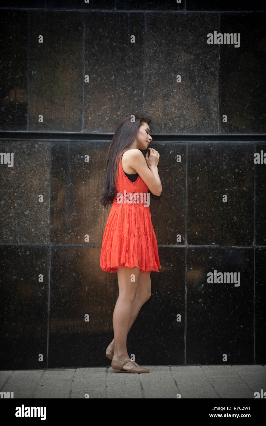 Young woman leaning against wall outdoors Banque D'Images