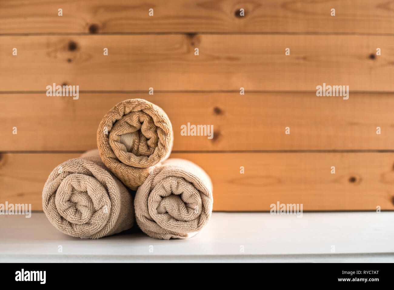 Serviettes de bain roulé sur fond de bois. Banque D'Images
