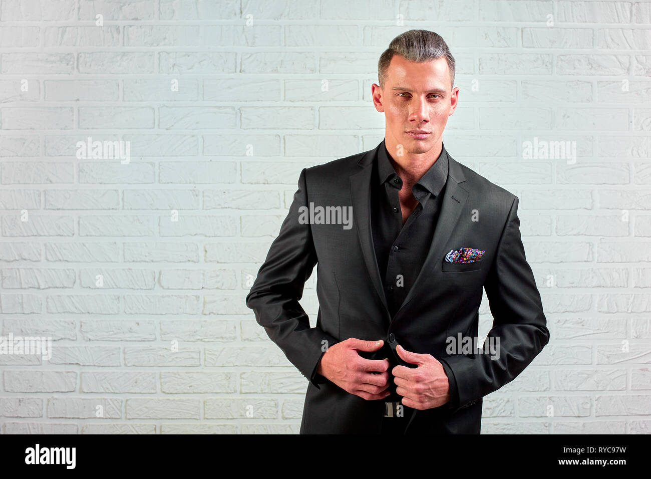 Portrait of handsome businessman en costume noir debout sur wall background copy space Banque D'Images