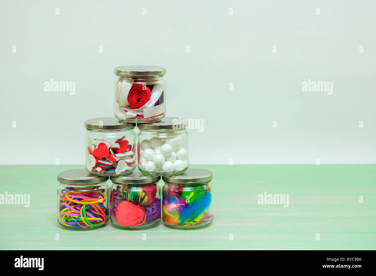 Pots de verre remplis de fournitures d'artisanat avec un fond blanc Banque D'Images
