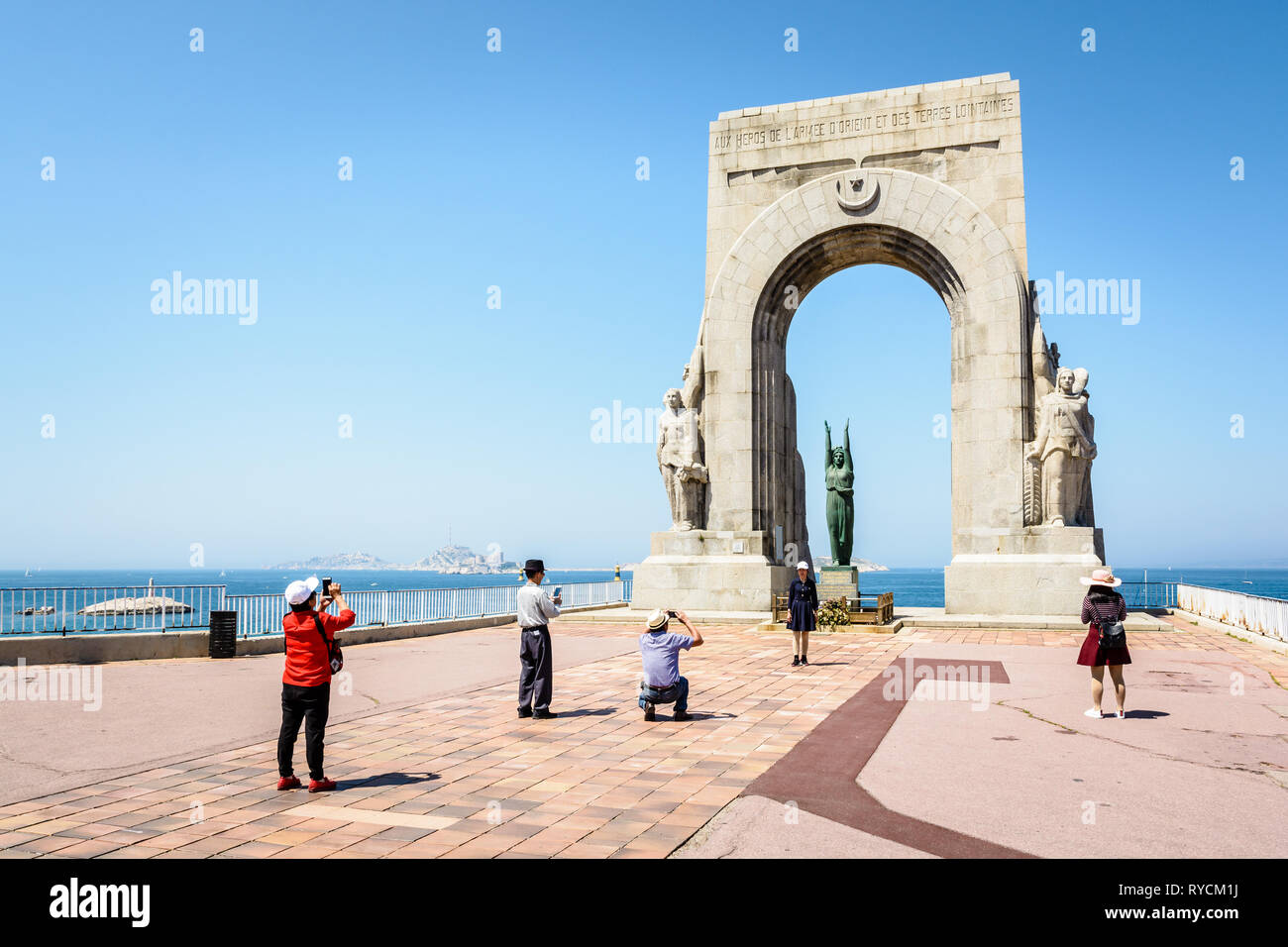Une famille de touristes chinois à prendre des photos de l'autre devant le monument à l'Armée de l'Est, connu comme la Porte d'Orient, à Marseille, France. Banque D'Images