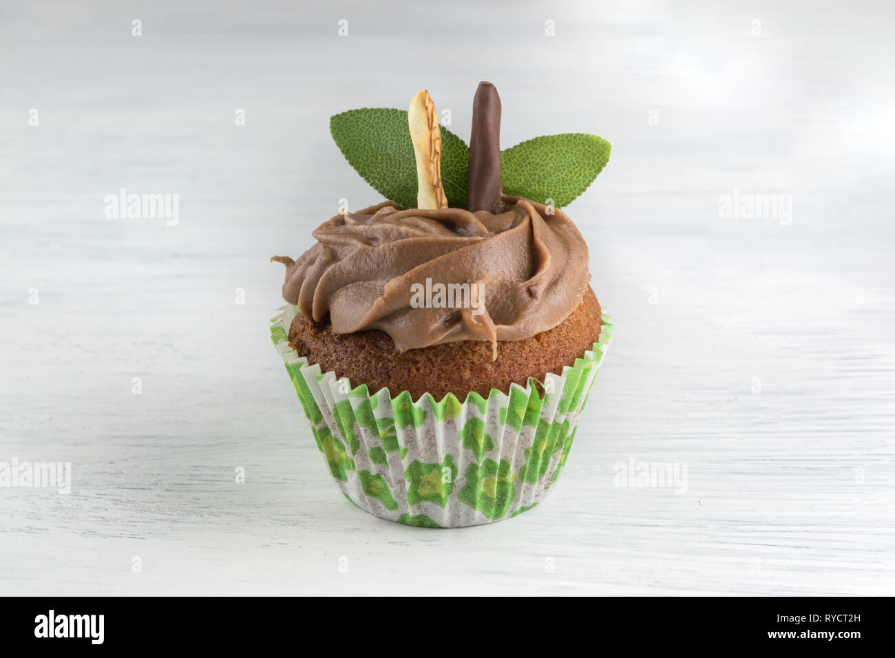 Cupcake chocolat isolé sur fond de table blanc avec des feuilles de menthe. Muffin pâtisserie Banque D'Images