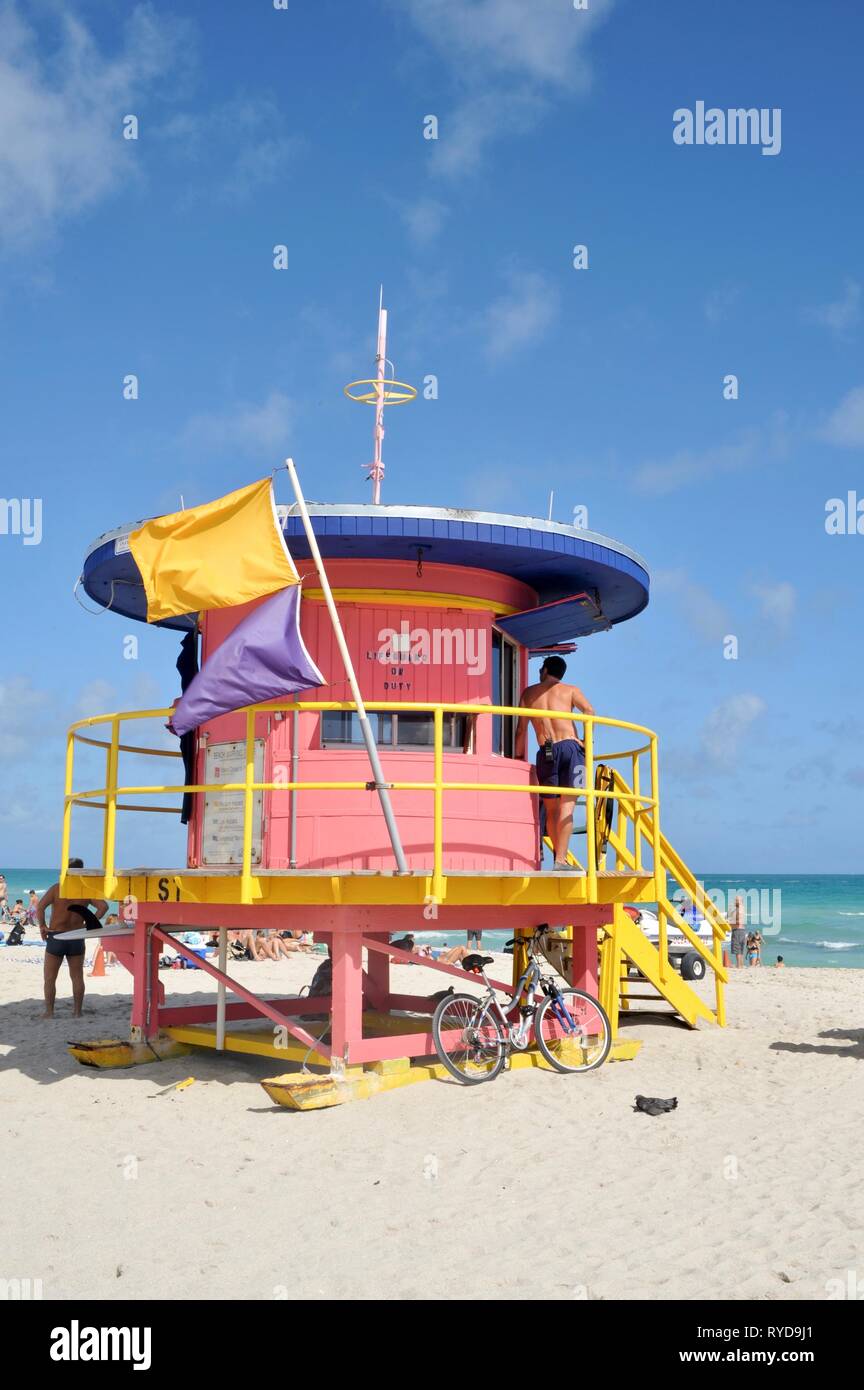 Art déco peint coloré lifeguard station sur sunny South Beach avec jaune et violet drapeaux alerte surf par fort vent, Miami, Floride, USA Banque D'Images