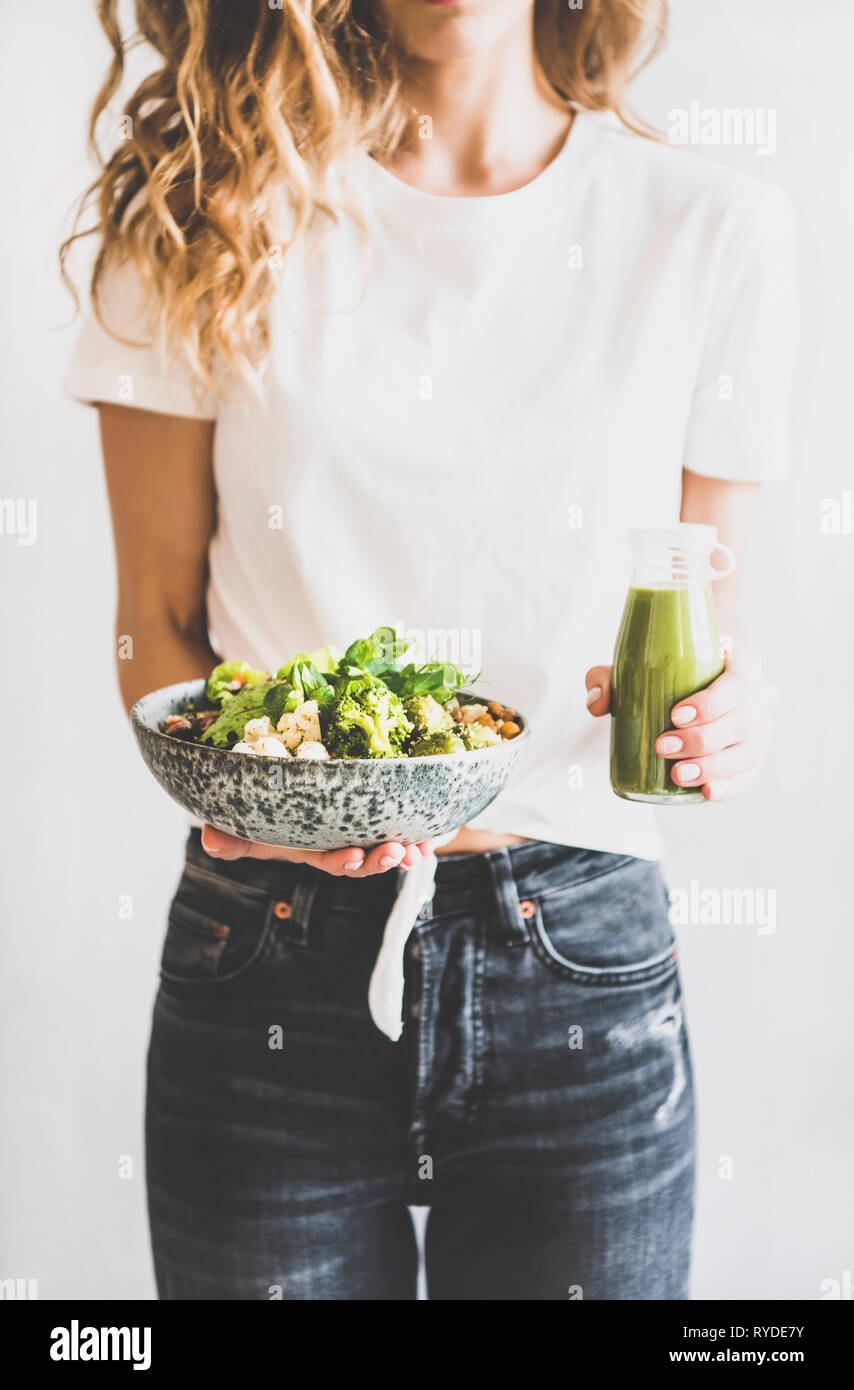 Dîner, déjeuner sain. Femme en jeans debout et tenant superbowl vegan ou Bouddha bol d'hummus, légumes, salade, haricots, couscous et avo Banque D'Images