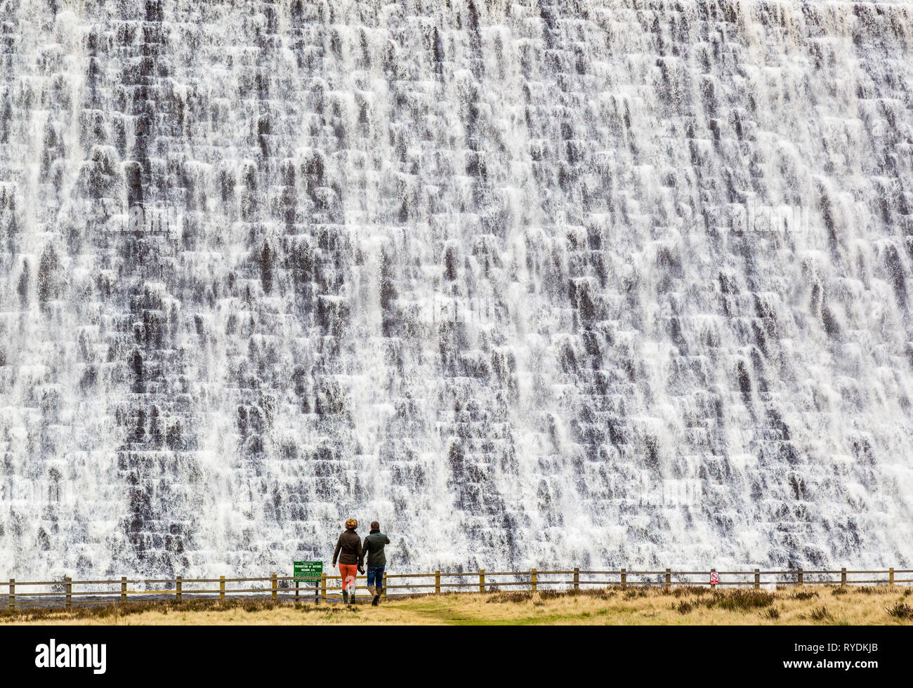Un couple de l'eau regarder le débordement du réservoir Derwent mur de barrage dans le Derbyshire Peak District après des semaines de forte pluie Banque D'Images