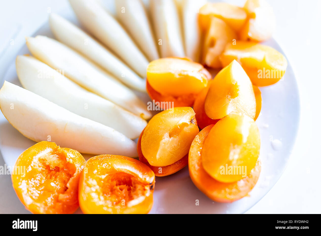 Libre de couper le fruit poire ou des tranches de pomme et d'abricot les moitiés de prunes sur plaque blanche et macro orange jaune couleur vibrante snack Banque D'Images