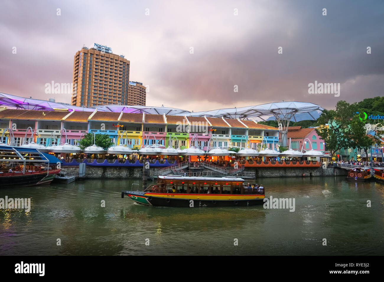 Coucher Soleil nuages roses colorées sur Clarke Quay, où les touristes ride bateaux le long de la rivière Singapour. Banque D'Images