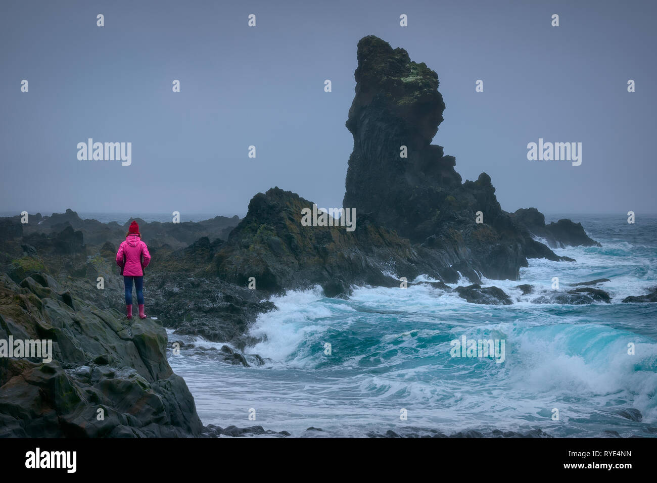 Photo de paysage de l'Islande et aventureux qui brave fille trônant fièrement en face de gros rocher près de vagues dangereuses à l'image. Banque D'Images