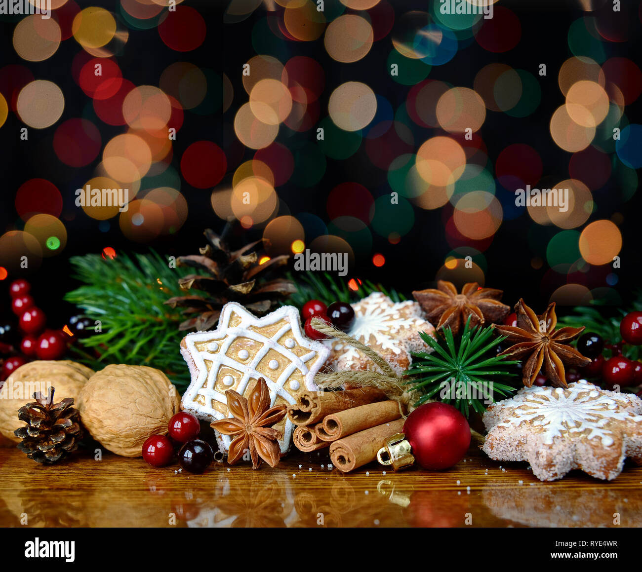 Belle composition avec gingerbread cookies de Noël, branches d'épinette, les noix, la cannelle et la badiane sont sur l'arrière-plan de lumières colorées Banque D'Images