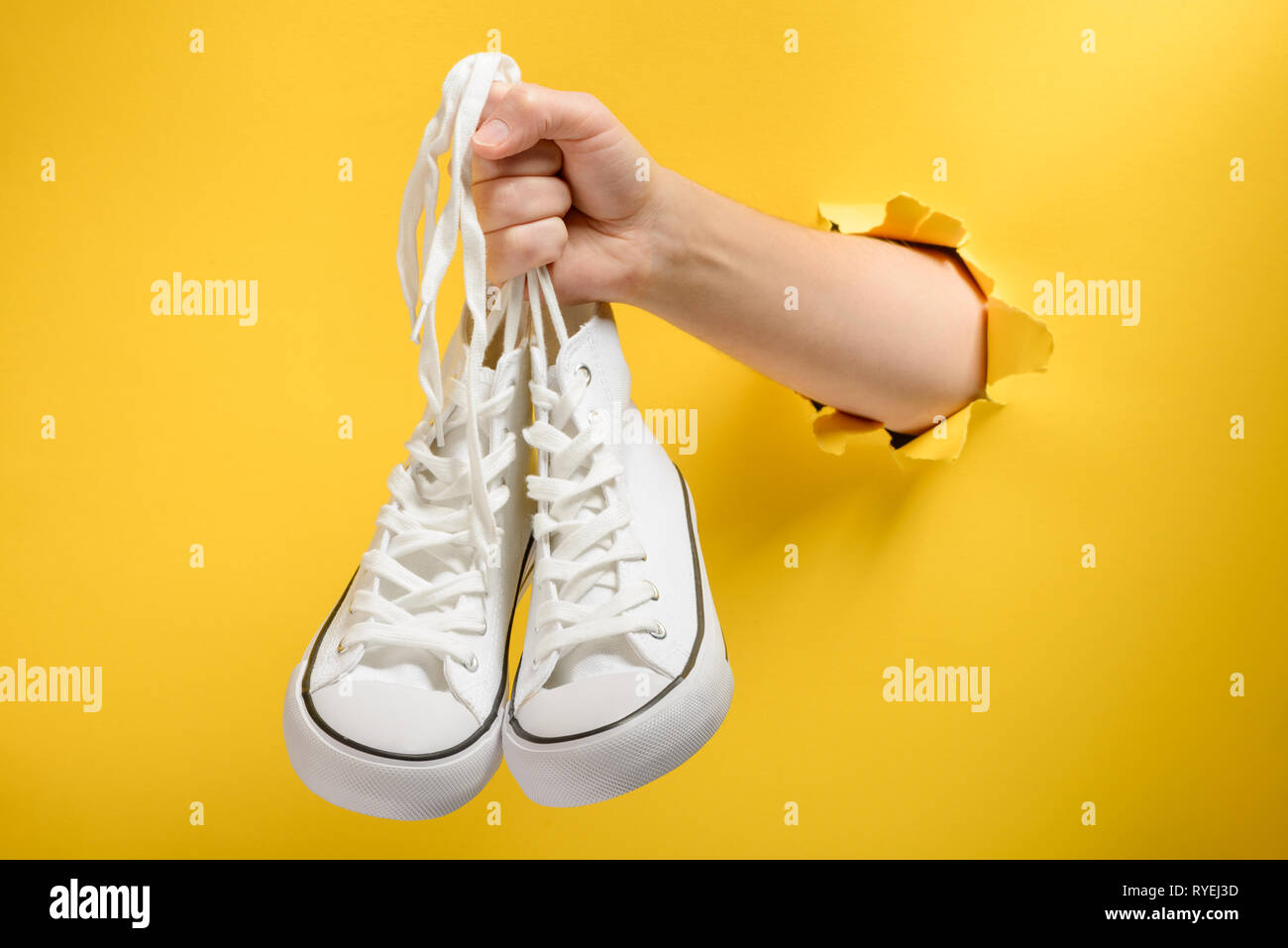 Hand holding white sneakers Banque D'Images