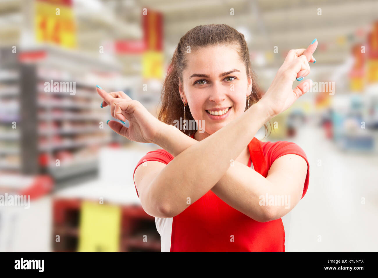 Hypermarché supermarché femelle ou travailleur souhaiter bonne chance avec les doigts croisés et geste d'armes Banque D'Images