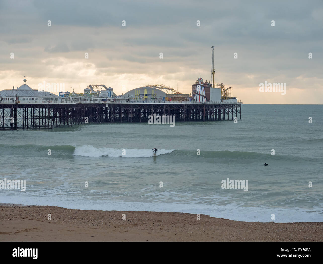 Les surfeurs bravant le froid décembre par la mer sur la jetée de Brighton couvert journée d'hiver. Banque D'Images