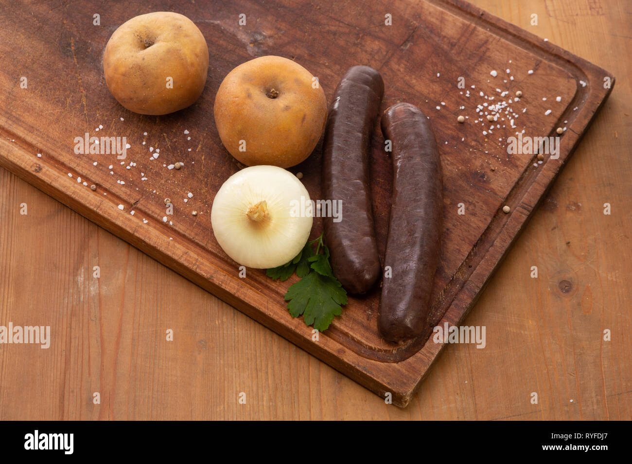 Boudin noir boudin pomme brut sur une planche à découper avec persil oignon apple Banque D'Images