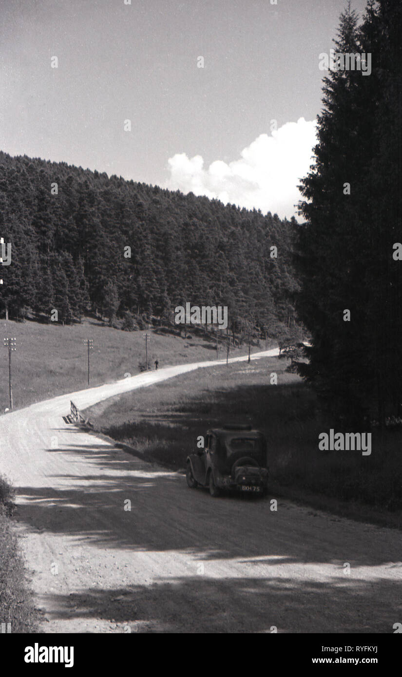 Années 1930, la Tchécoslovaquie, une voiture britannique de l'ère garé sur une route de campagne de gravier, à côté d'une forêt tournée du pays dans cette pré-ww2 ère. Banque D'Images