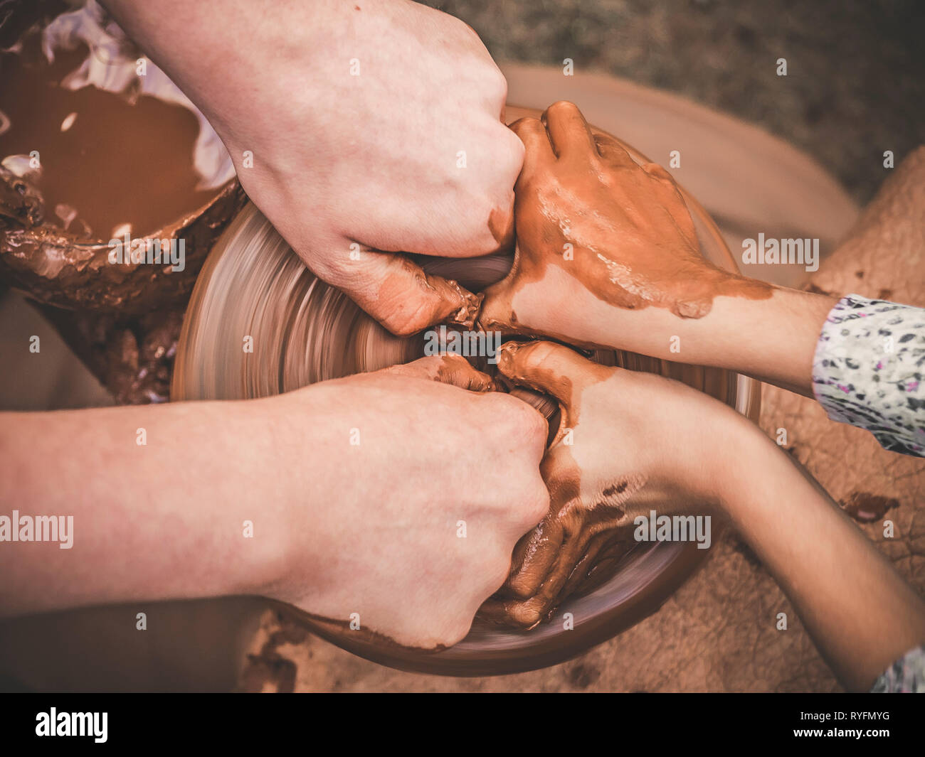 Un carftman poterie enseignement directeurs les mains d'un enfant part, montrant la façon de lancer un pot en argile sur une roue de potier. L'enseignant et l'apprenant concept. Vue d'en haut Banque D'Images