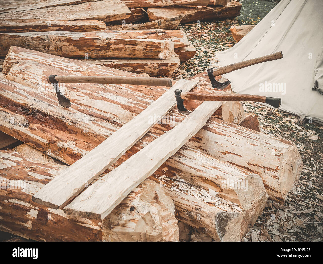 Site de construction. Bois de chauffage avec axes sur une nature. De nombreux journaux planche en bois et trois axes à l'extérieur. Construction d'une écorce de bois. Banque D'Images