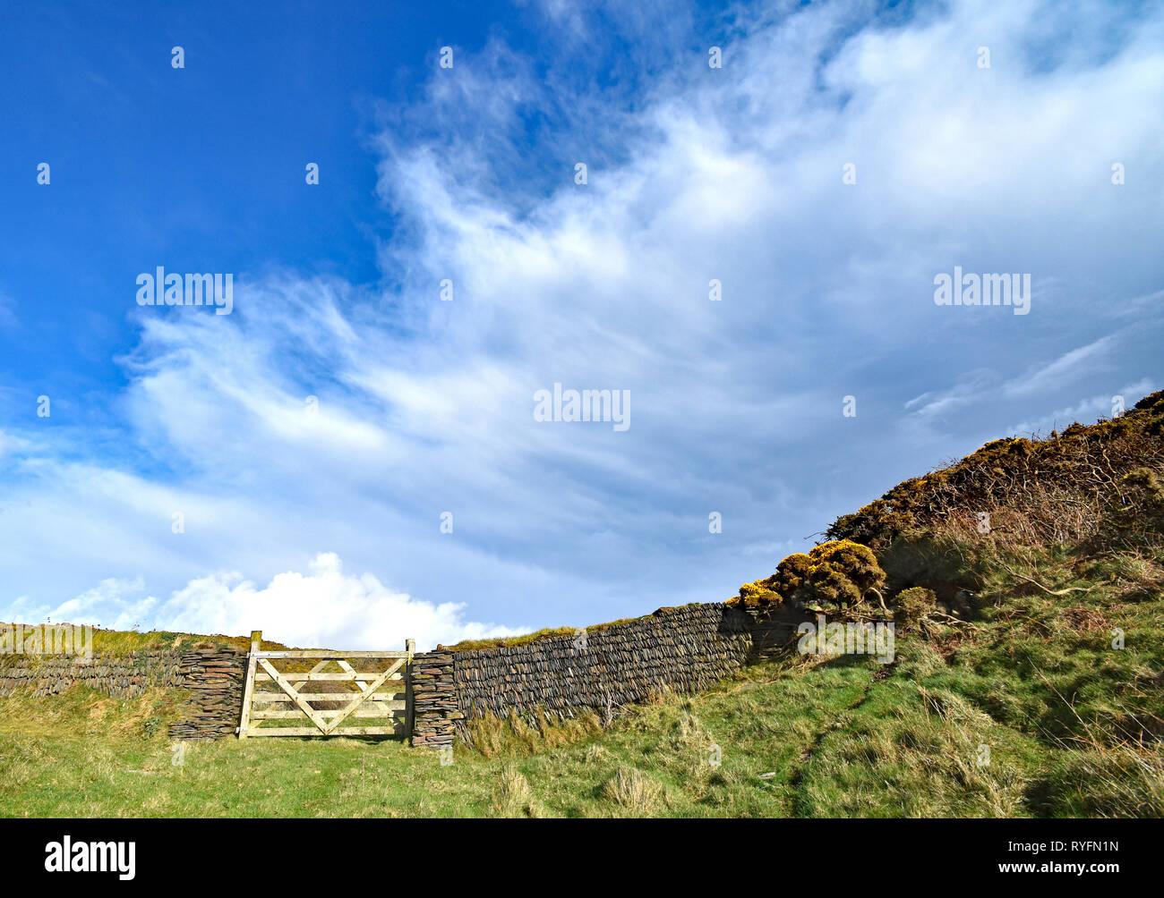 Porte d'entrée sur le terrain en bois et mur de pierres sèches, à Morthe Point, North Devon, Angleterre. Banque D'Images