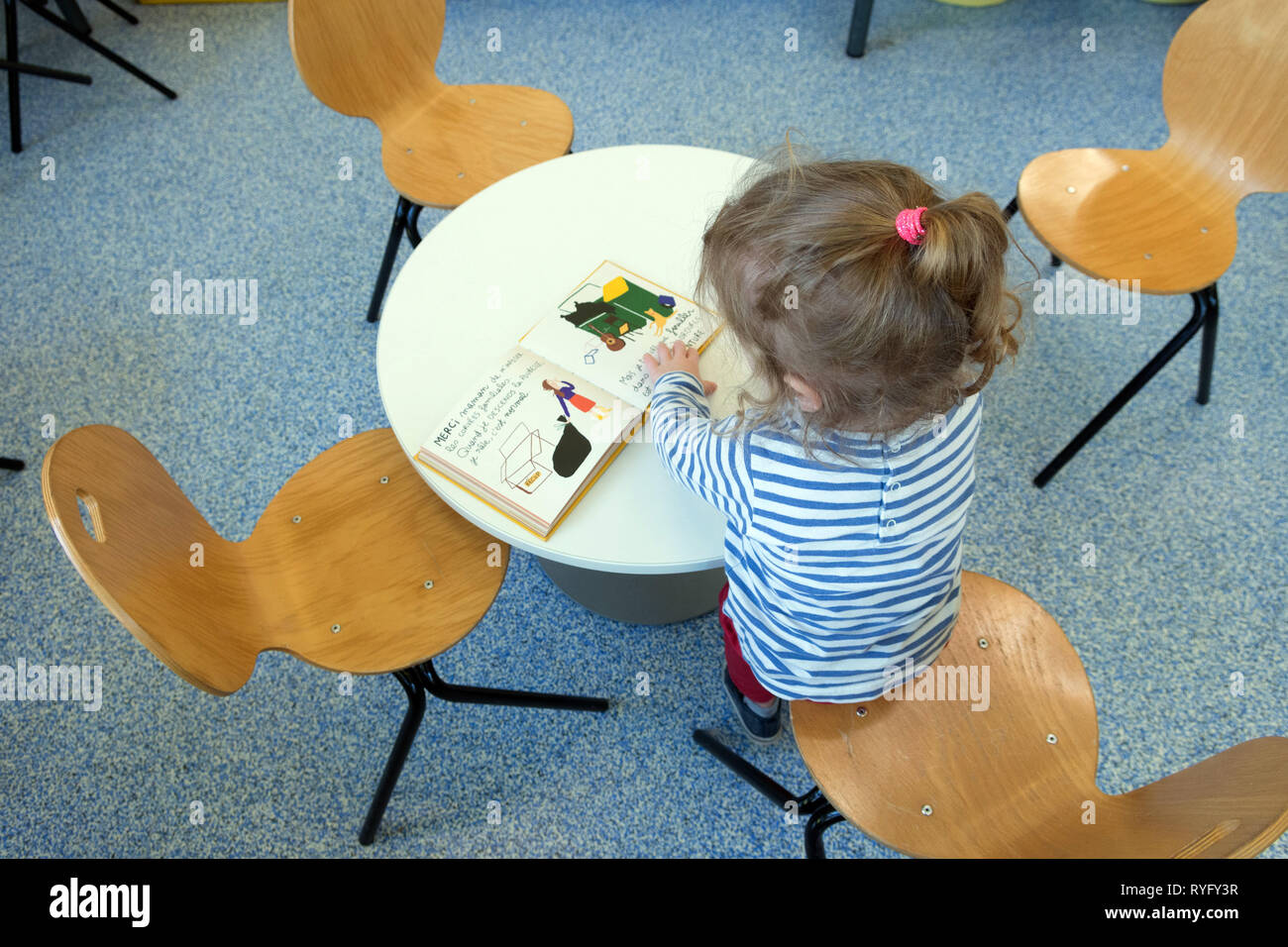 Petite fille à la recherche d'un livre dans une bibliothèque Banque D'Images