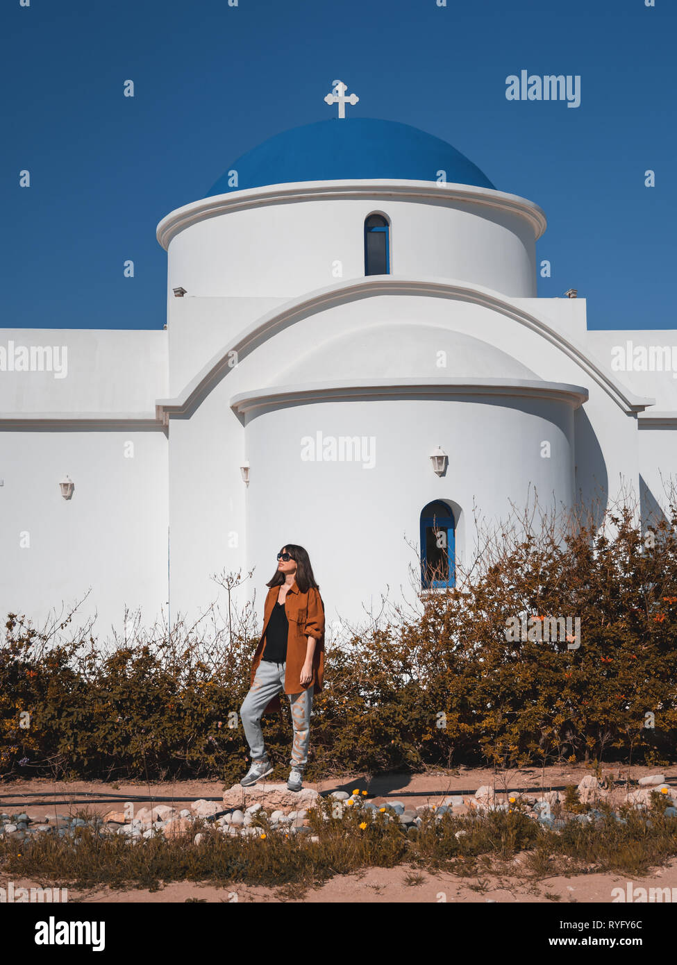 Belle jeune fille en face de bleu et blanc classique de l'Église grecque orthodoxe de Saint Nicolas à Paphos, Chypre Banque D'Images