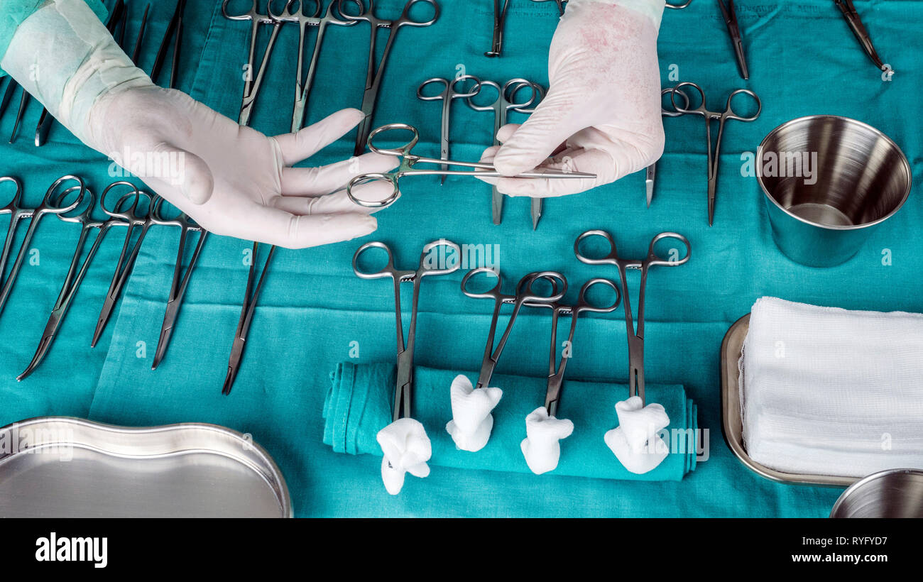 Chirurgien travaillant en salle d'opération, les mains avec des gants holding scissors sutures, conceptual image, composicon l'horizontale Banque D'Images