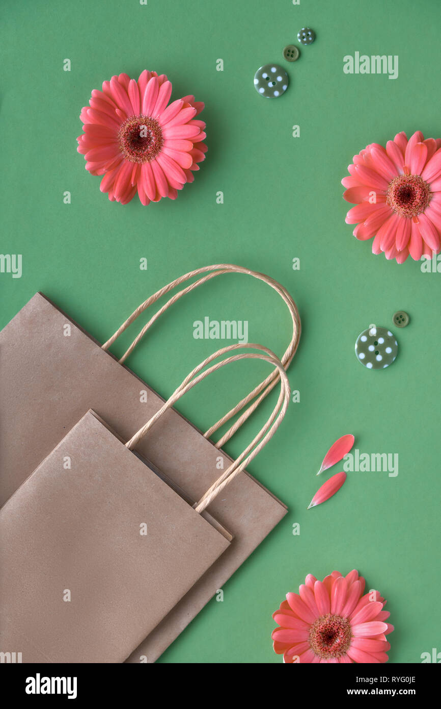 Gerbera fleurs corail daisy et d'artisanat sacs papper sur papier vert, fond printemps vente concept image avec l'espace de copie Banque D'Images