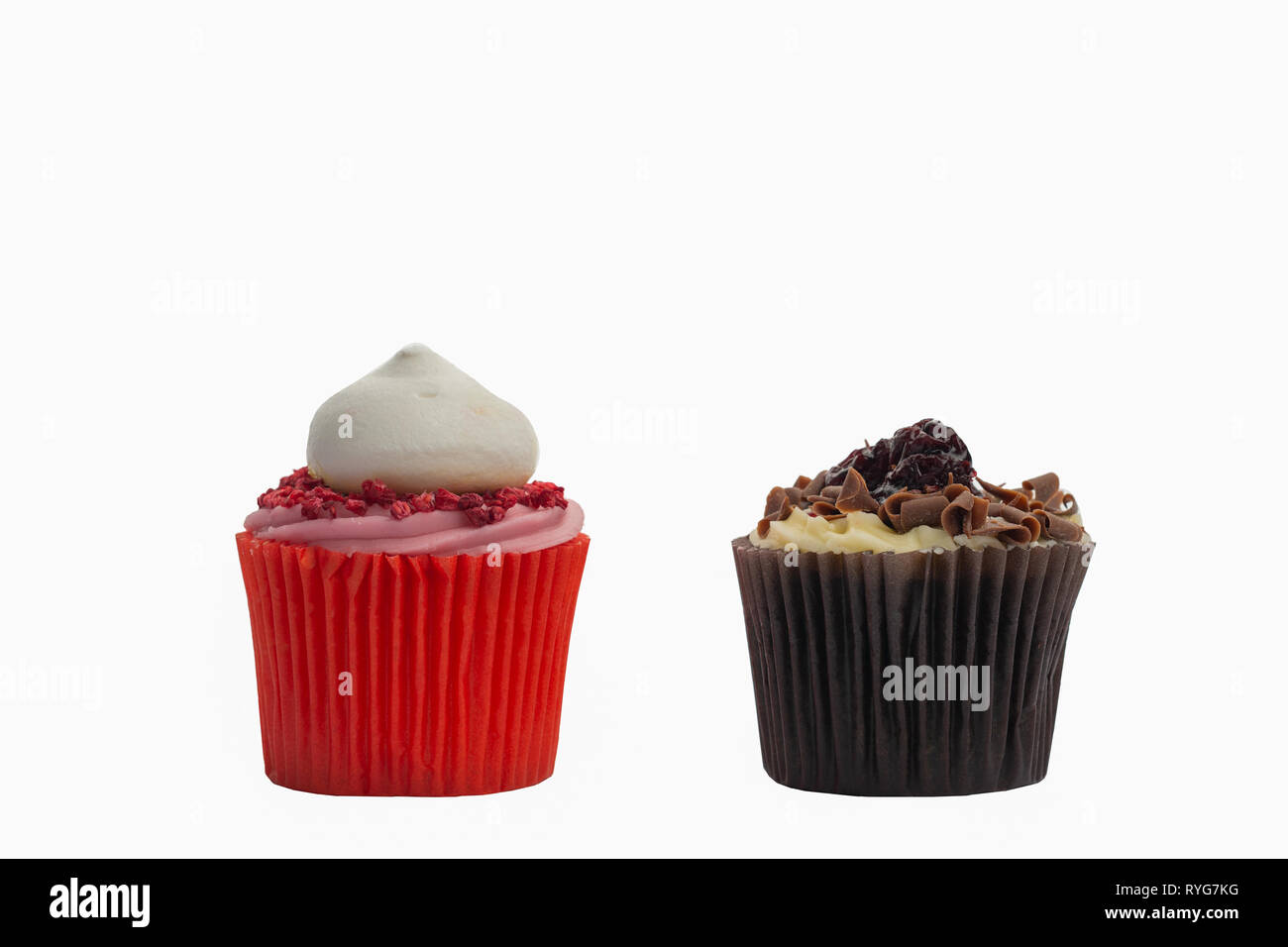 En cas Cupcake papier rouge avec glaçage rose et de framboises sur le dessus et au chocolat Gâteau de fée de la forêt-noire sur blanc, selective focus Banque D'Images