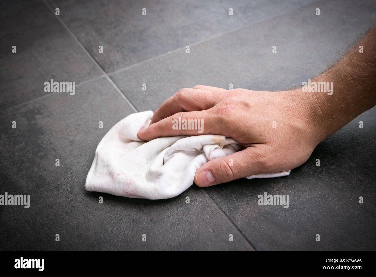 La main de l'homme au chiffon propre lingettes installée récemment vinyl flooring. Banque D'Images