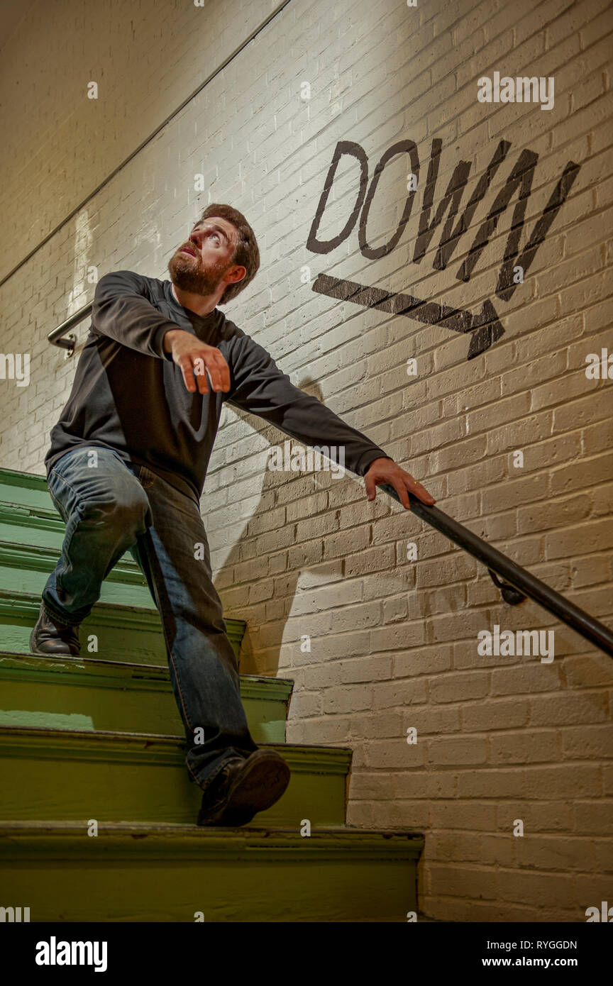 Homme barbu brouille descendre un escalier dans la peur ou la terreur avec une flèche vers le chemin de ses directeurs Banque D'Images