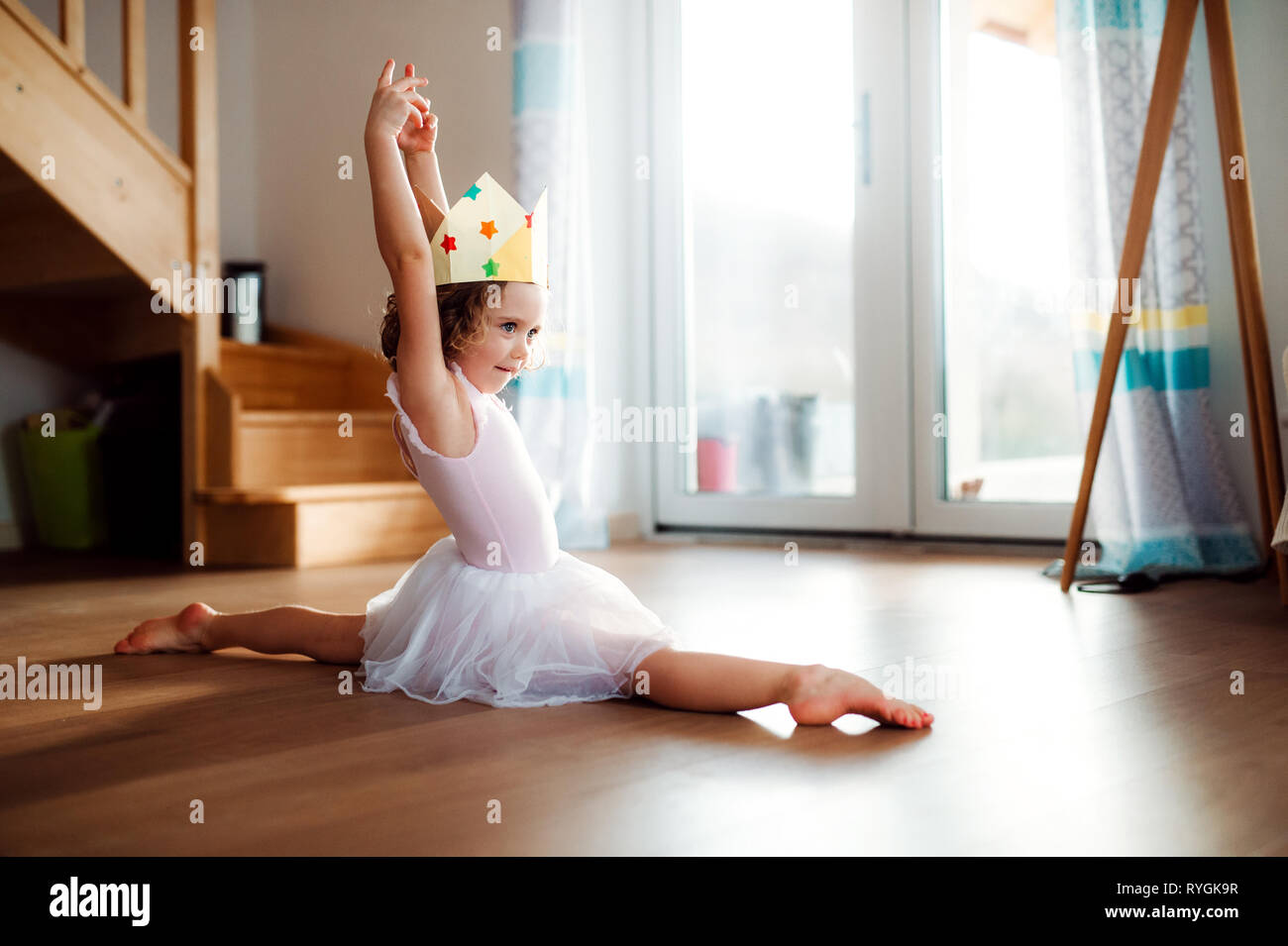 Une petite fille princesse ballerine avec une couronne à la maison, faisant  gymnastic split Photo Stock - Alamy