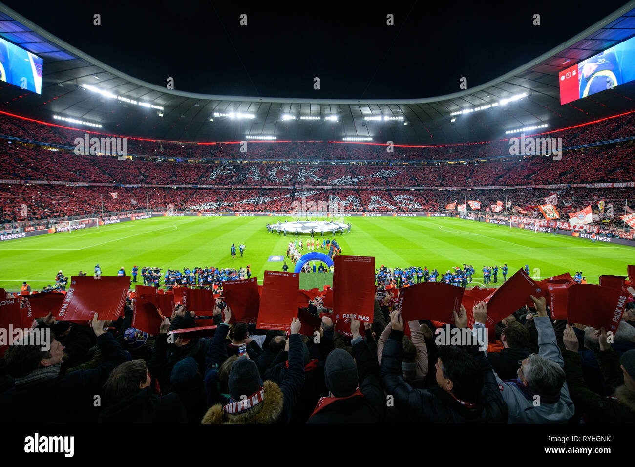 Munich, Allemagne. Mar 13, 2019. Football : Ligue des Champions, knockout ronde, ronde de 16 ans, deuxième étape : FC Bayern Munich - FC Liverpool dans l'Allianz Arena. Les équipes de Liverpool (l) et le FC Bayern Munich sont debout sur le terrain avant le début du match, alors que les fans se forment les mots 'pack' Mas avec papier glisse en arrière-plan. Credit : Matthias Balk/dpa/Alamy Live News Banque D'Images