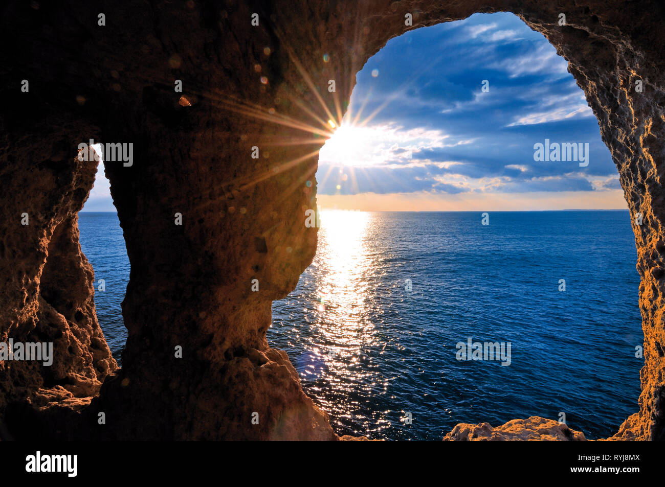 Le coucher du soleil romantique vue à travers un rock arch Banque D'Images