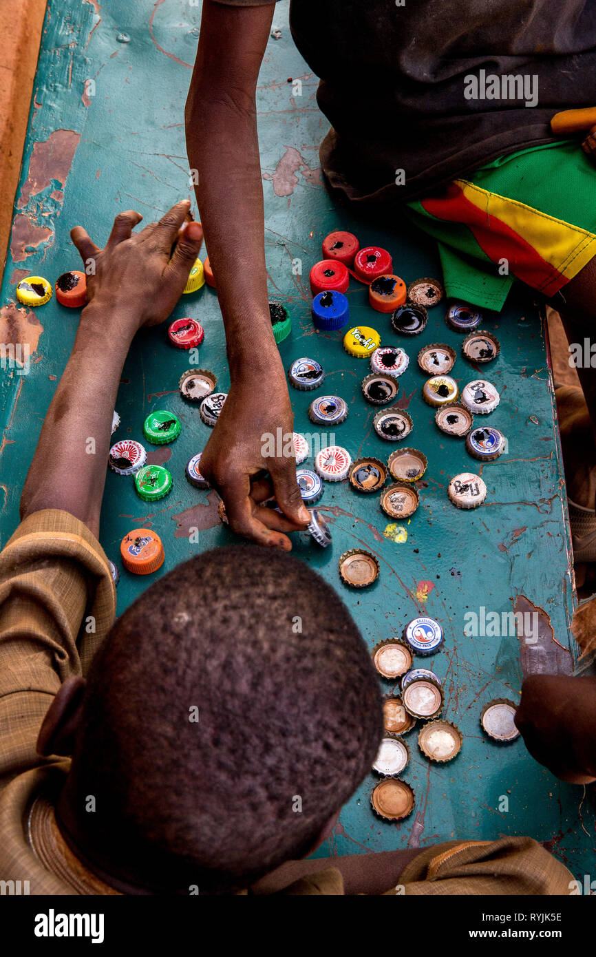 ICCV Nazemse ONG à Ouagadougou, Burkina Faso. Garçons jouant avec des capsules de bouteille. Banque D'Images
