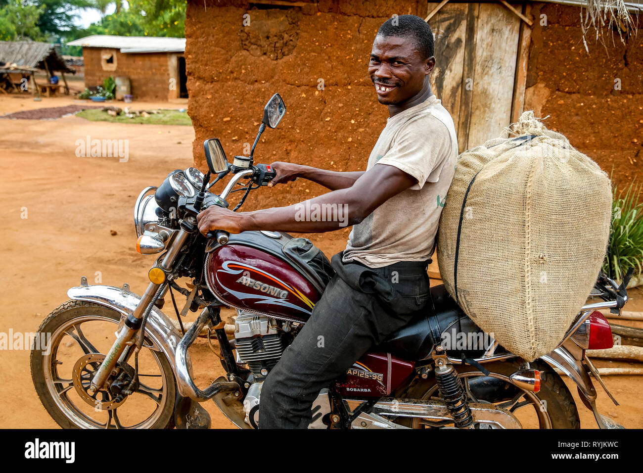 Semoir cacao la conduite d'une moto dans un village près de Daloa, Côte d'Ivoire. Banque D'Images
