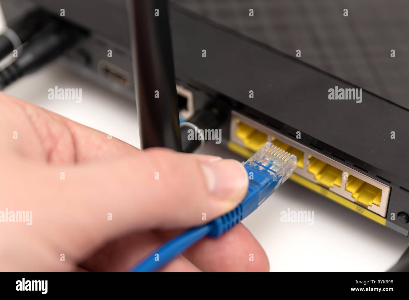 L'homme se branche à Internet par câble au routeur. Concept connexion Ethernet Banque D'Images