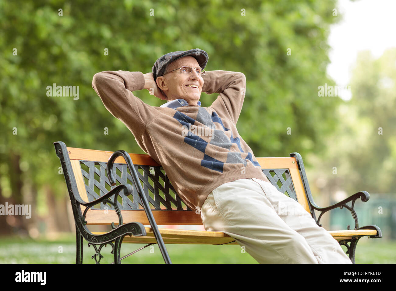 Homme âgé bénéficiant d'une journée sur un banc en bois dans le parc Banque D'Images
