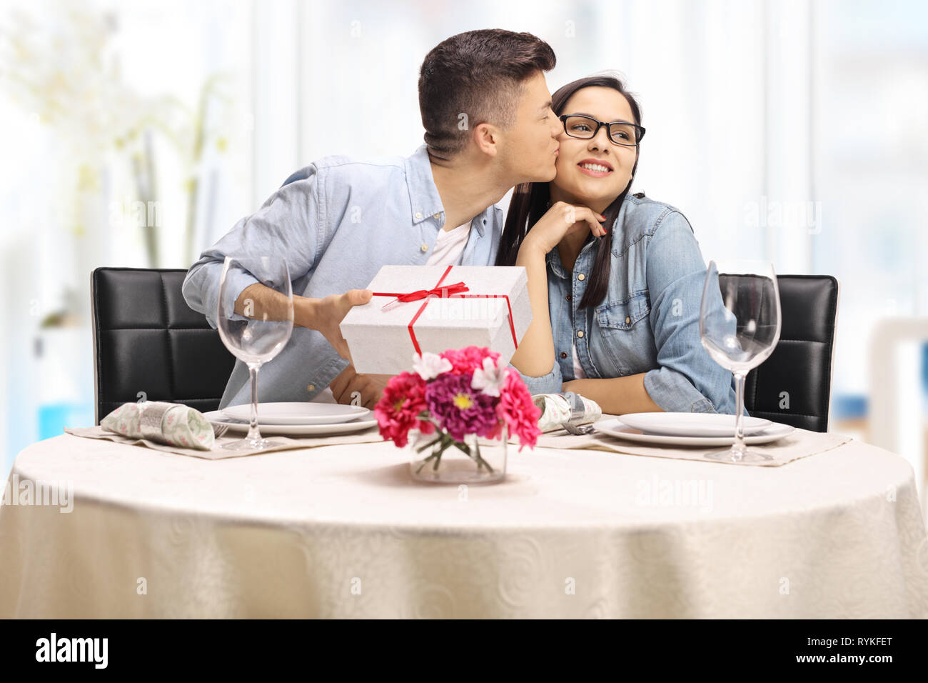 Jeune homme embrassant une fille et donner un présent à une table de restaurant Banque D'Images