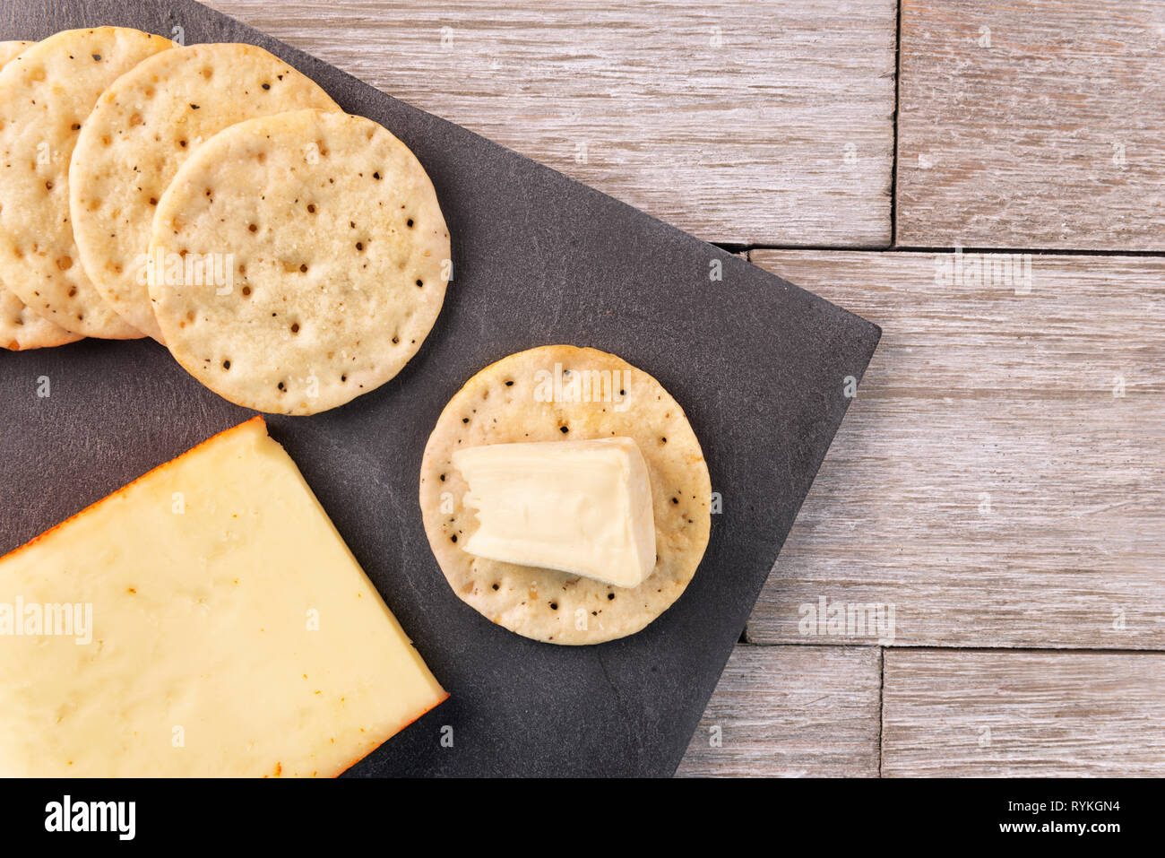 Les craquelins et assiette de fromage blanc sur planche de bois. L'alimentation hors-concept. Mise à plat. Banque D'Images