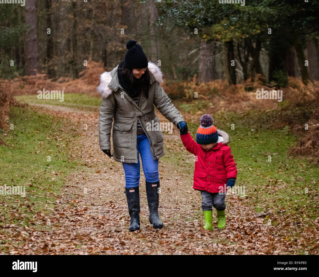 La mère et le fils marchant à travers la forêt en automne tenant les mains, porter des wellies Banque D'Images
