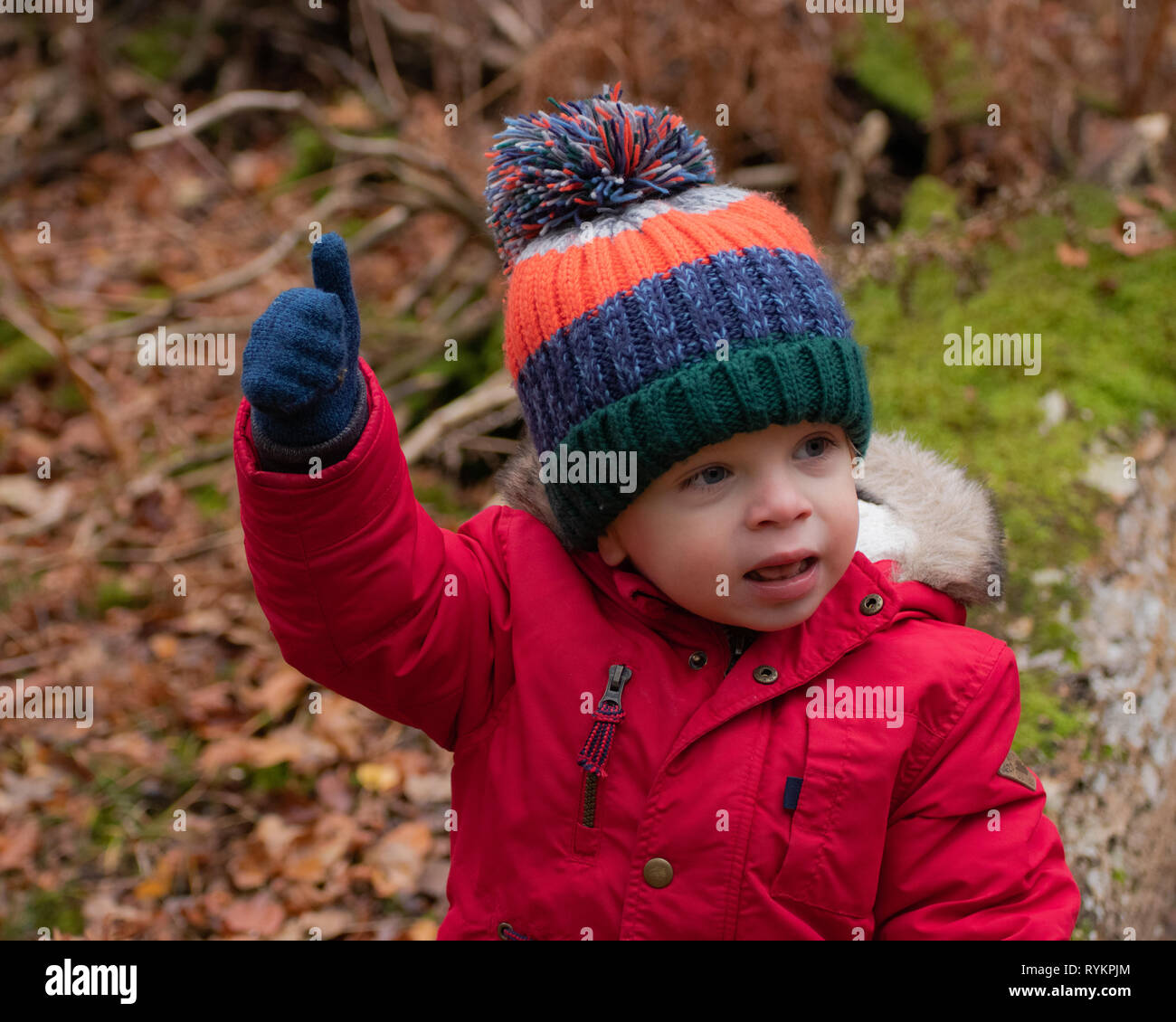 Petit garçon en veste rouge et bobble hat le pouce up sign Banque D'Images