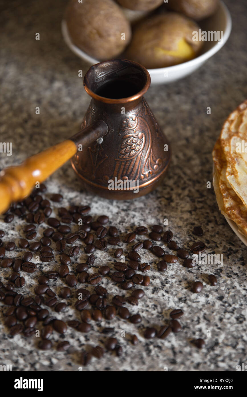 Cezve avec des grains de café et crêpes de pommes de terre bouillies dans l'arrière-plan Banque D'Images