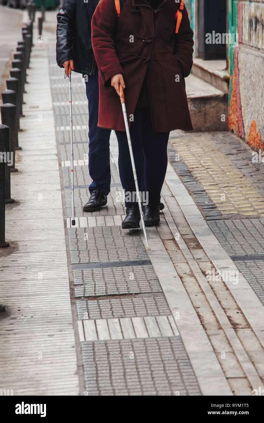 Blind man and woman walking on the street en utilisant une canne blanche Banque D'Images