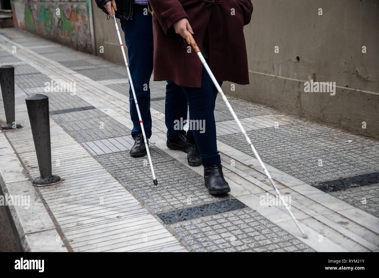 Blind man and woman walking on the street en utilisant une canne blanche Banque D'Images
