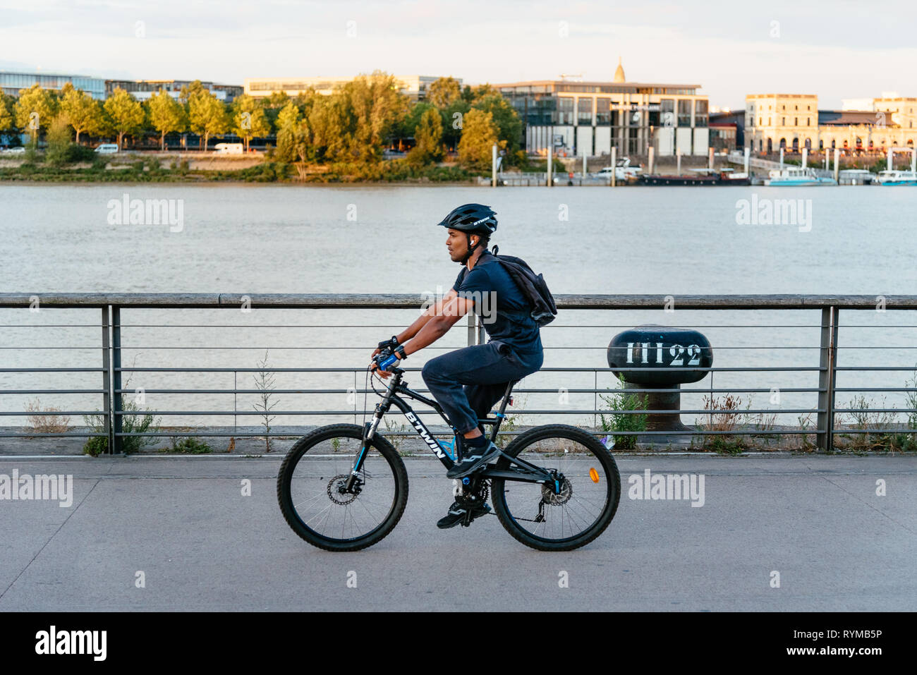 Bordeaux, France - Juillet 22, 2018 : Jeune homme d'une bicyclette par riverside Banque D'Images